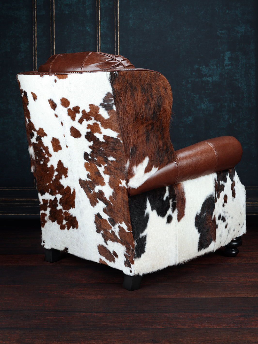 Bushwacker Leather and Cowhide Recliner with tri-colored cowhide on the outside back in a studio setting.