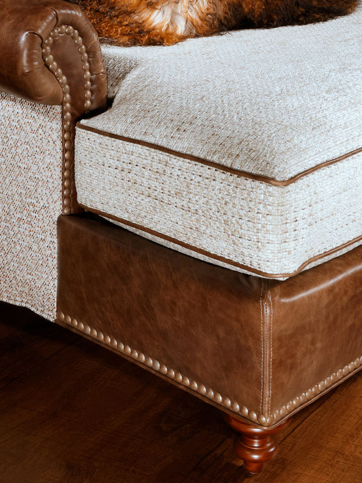 close up view of white fabric and brown leather chaise lounge