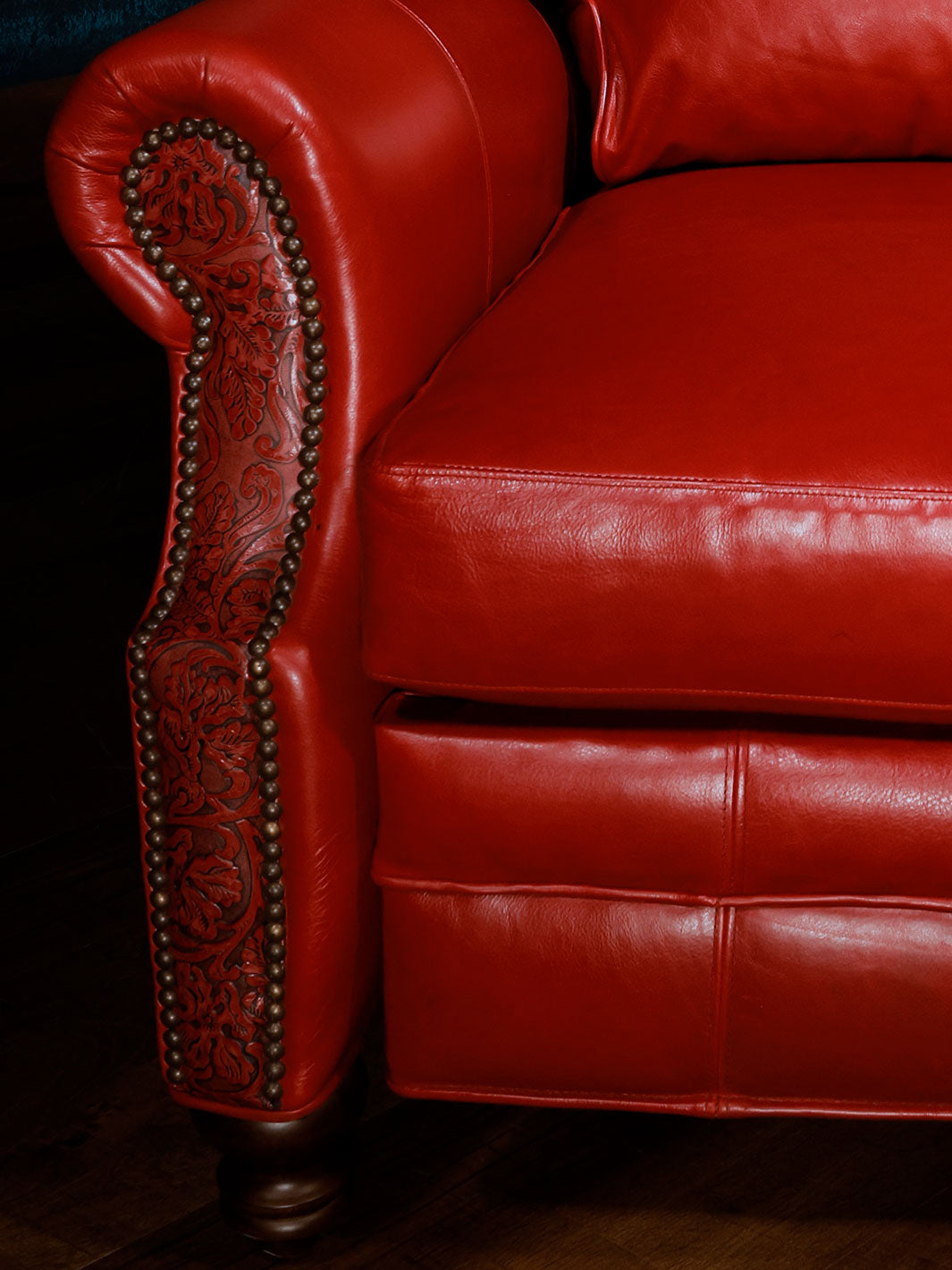 Red Rider Western Leather Recliner with red leather and Cowboy Tool embossed inlay with rolled arm design and silver nailheads in a close up view. 