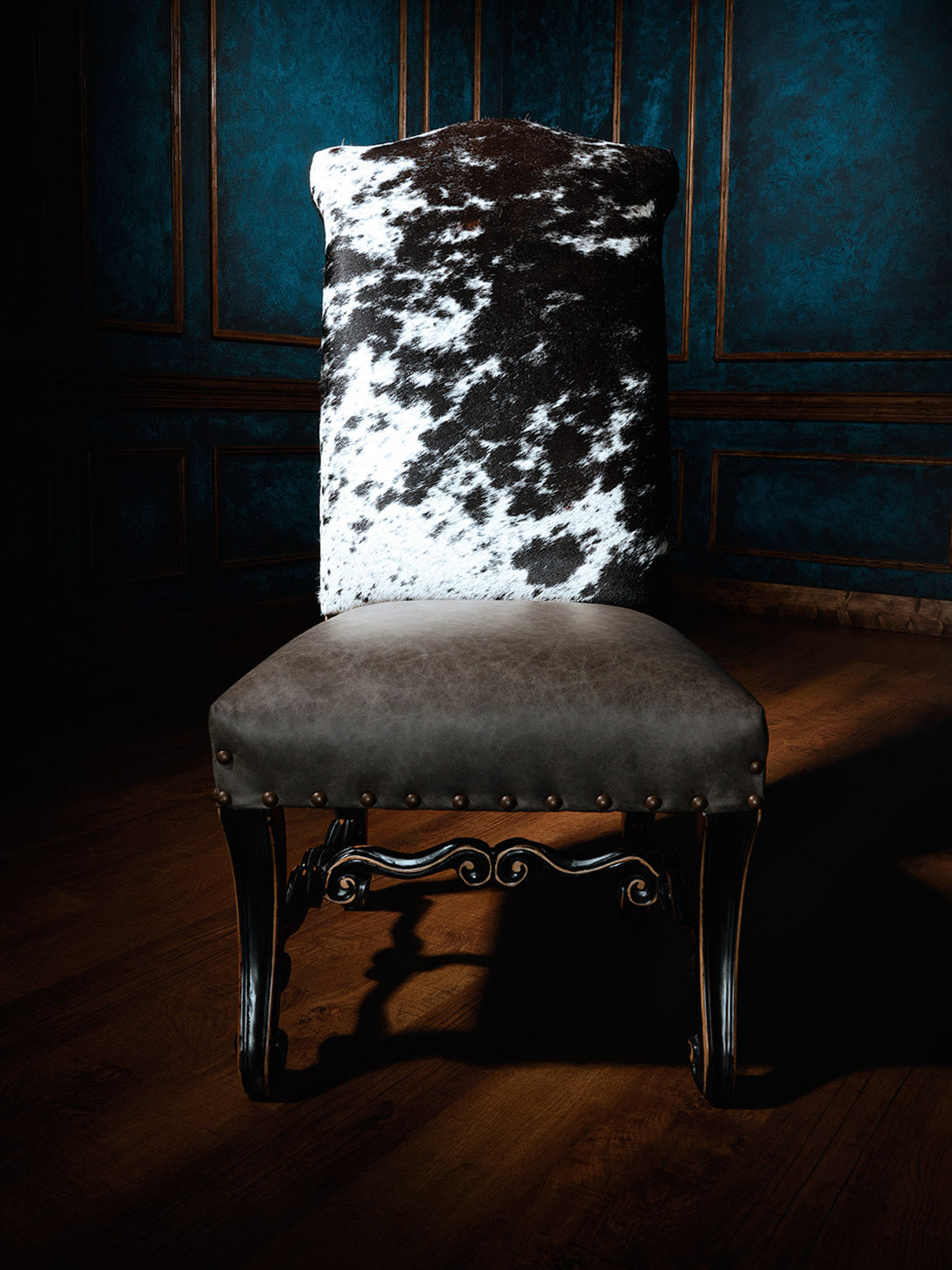 Texas Outlaw Cowhide Western Dining in full grain grey leather with speckled cowhide back in a moody dining space.