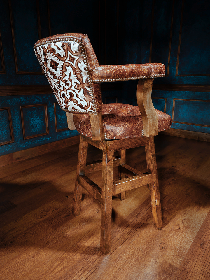 Texas Sunrise Chisum Western Bar Stool in full grain leather with embossed leather detailing in a rustic bar area.