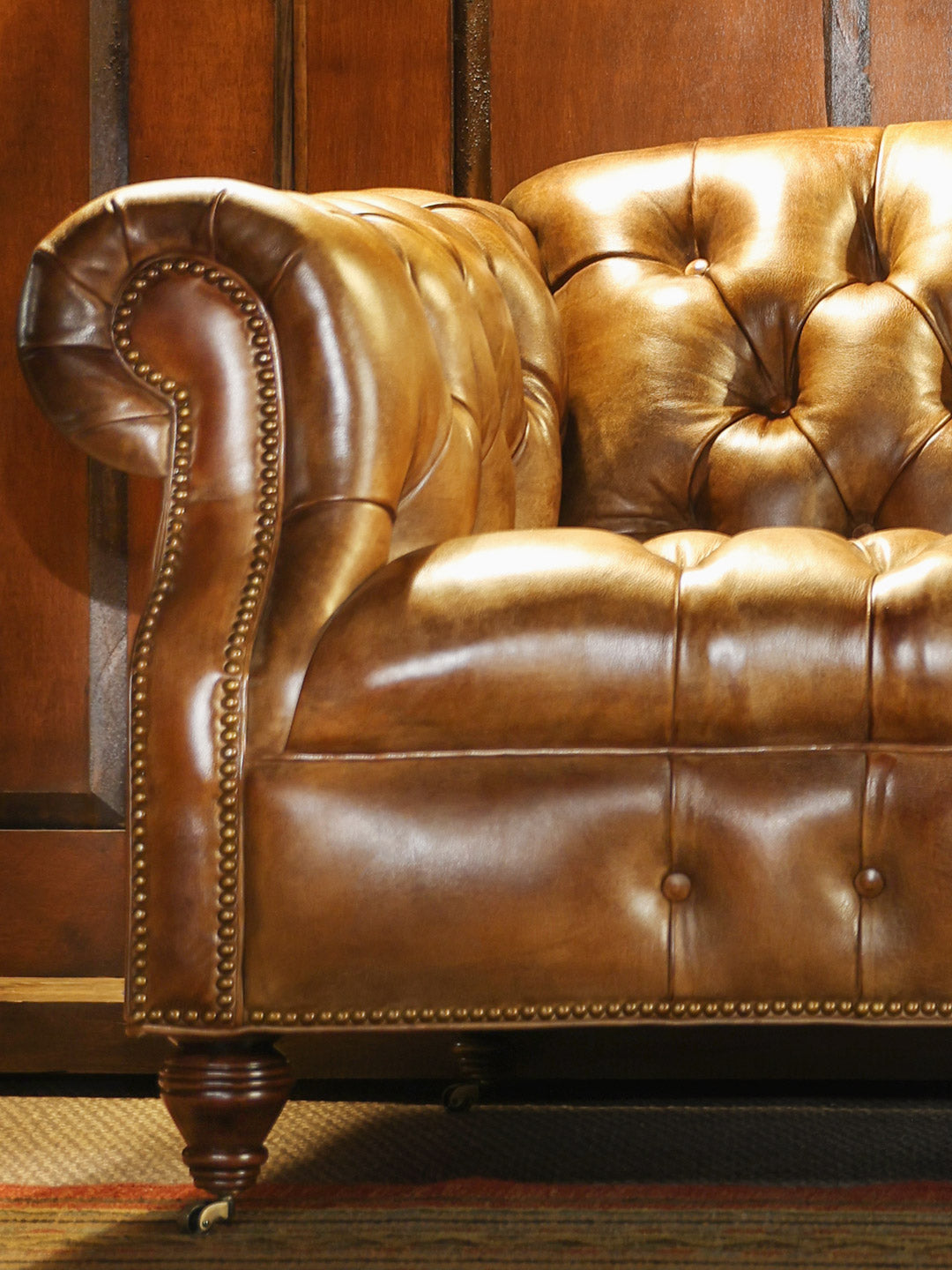 Weston Cane Chesterfield Leather Sofa with a classic rolled arm design and gold nailhead trim detailing in a close up view.